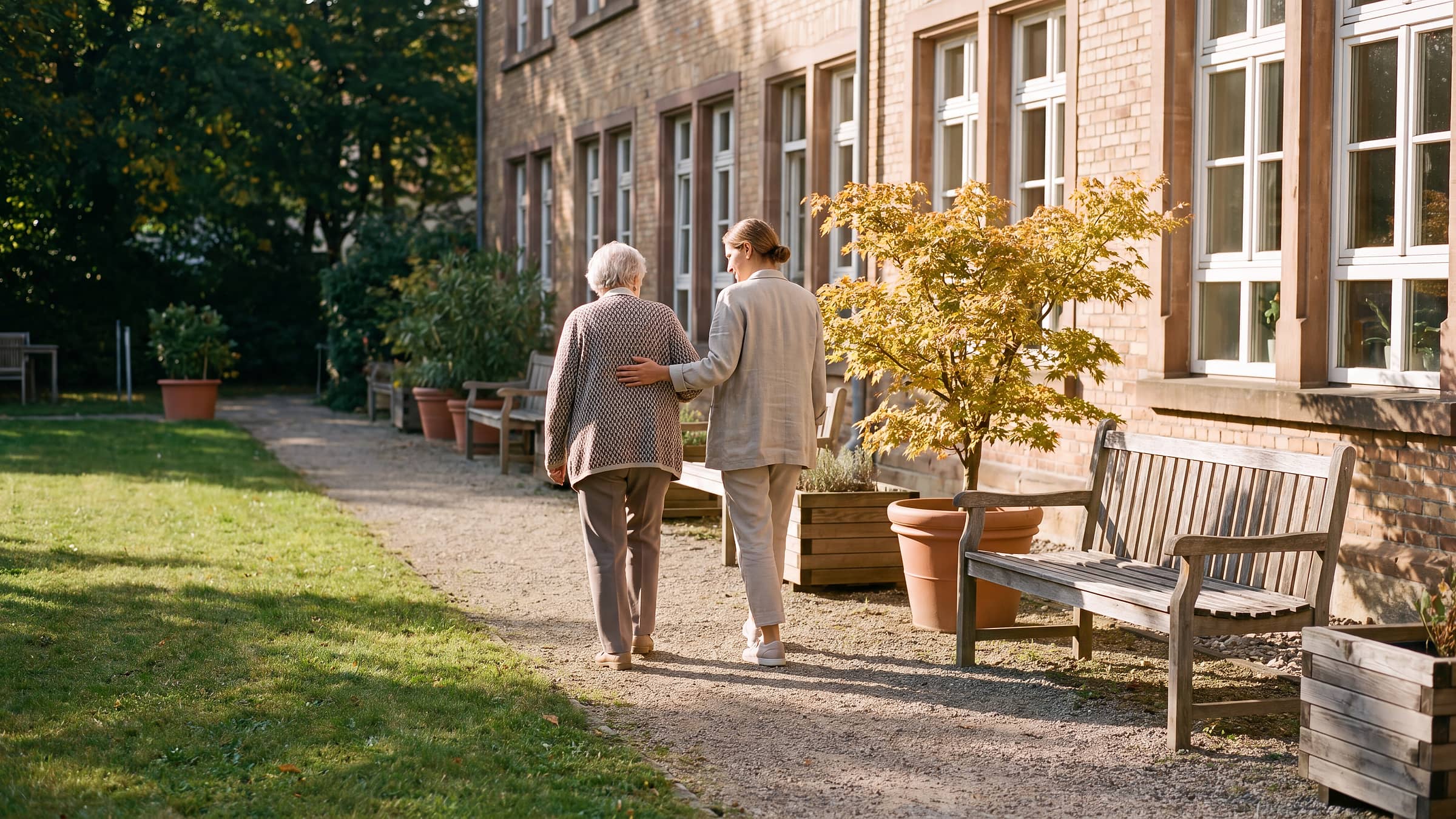 Sonniger Gemeinschaftsgarten eines deutschen Pflegeheims mit Bewohnern und Angehörigen